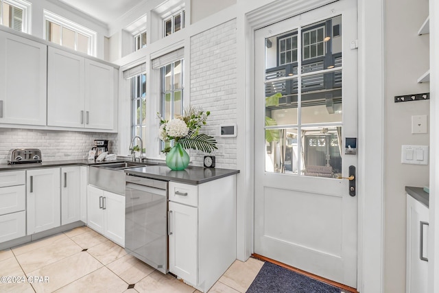 kitchen with dishwasher, backsplash, white cabinets, ornamental molding, and light tile patterned floors