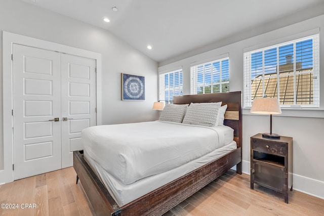 bedroom featuring lofted ceiling, light wood-type flooring, and a closet