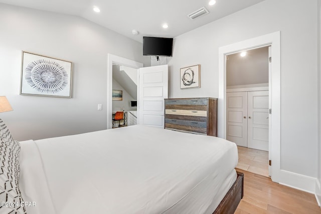 bedroom with a closet, lofted ceiling, and light hardwood / wood-style flooring