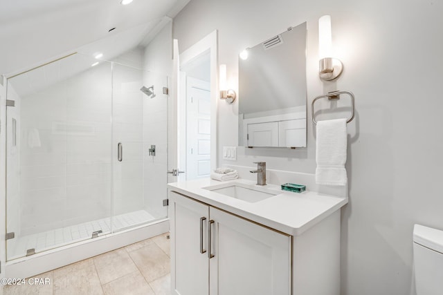 bathroom with tile patterned floors, vaulted ceiling, toilet, vanity, and a shower with shower door