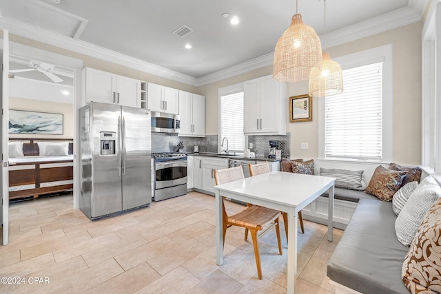 kitchen with decorative backsplash, stainless steel appliances, white cabinetry, and hanging light fixtures