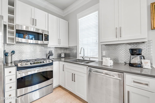 kitchen featuring backsplash, sink, ornamental molding, white cabinetry, and stainless steel appliances