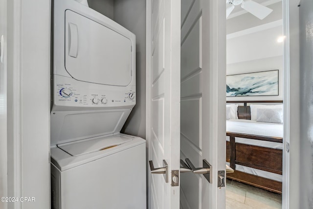 laundry room with stacked washing maching and dryer, ceiling fan, and light tile patterned flooring