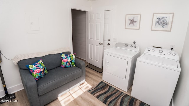 clothes washing area featuring electric panel, separate washer and dryer, and light hardwood / wood-style floors