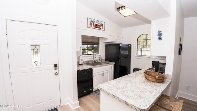 kitchen featuring lofted ceiling, white cabinets, black appliances, and plenty of natural light