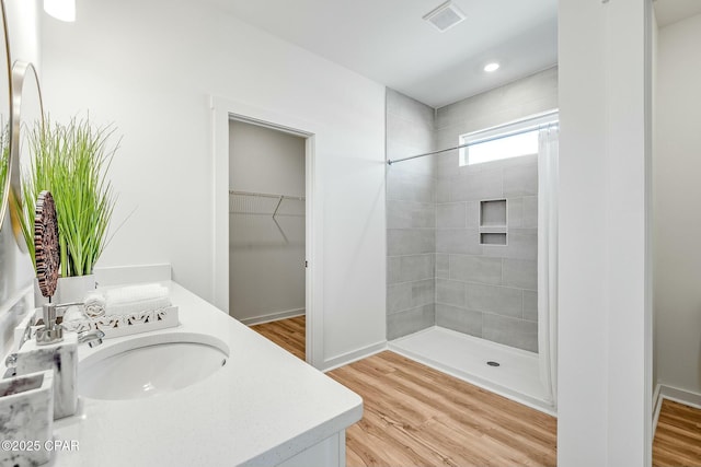 bathroom with vanity, wood-type flooring, and tiled shower