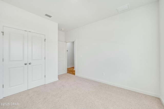 unfurnished bedroom with light carpet and a closet