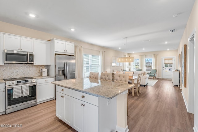 kitchen featuring white cabinetry, tasteful backsplash, appliances with stainless steel finishes, a kitchen island, and light hardwood / wood-style floors