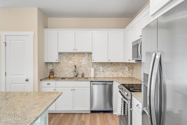 kitchen featuring appliances with stainless steel finishes, tasteful backsplash, white cabinetry, sink, and light stone countertops