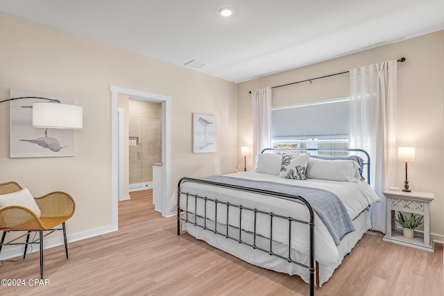 bedroom with ensuite bathroom and light wood-type flooring