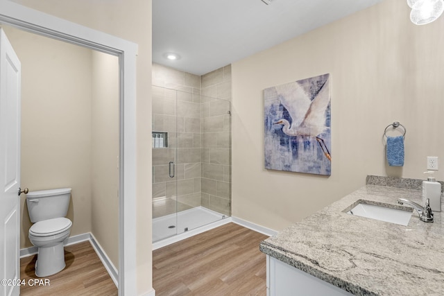 bathroom with a shower with door, vanity, hardwood / wood-style floors, and toilet