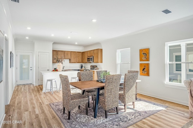 dining room with crown molding and light hardwood / wood-style floors