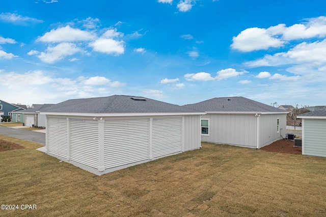 rear view of house featuring a yard and central AC unit