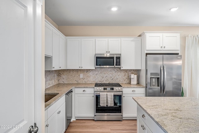 kitchen with stainless steel appliances, tasteful backsplash, and white cabinets