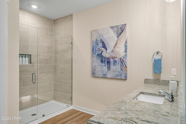 bathroom featuring hardwood / wood-style flooring, vanity, and a shower with door