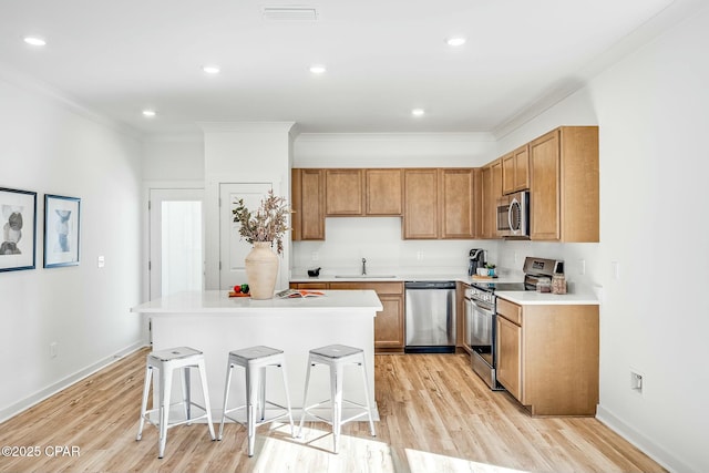 kitchen with a kitchen island, sink, a breakfast bar area, stainless steel appliances, and crown molding