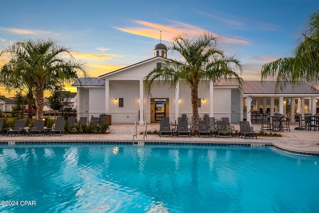 pool at dusk featuring a patio