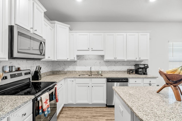 kitchen with white cabinetry, light wood-type flooring, stainless steel appliances, sink, and light stone counters