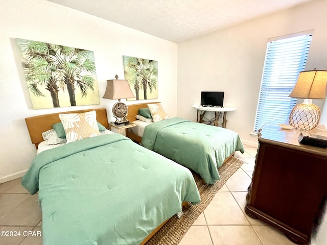 bedroom featuring tile patterned floors, baseboards, and a textured ceiling