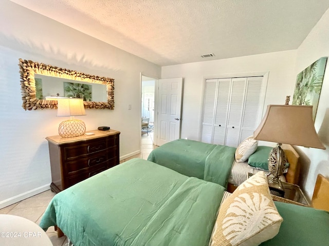 bedroom featuring a closet, a textured ceiling, and light tile patterned floors