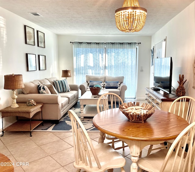 dining area with a chandelier, a textured ceiling, and light tile patterned floors