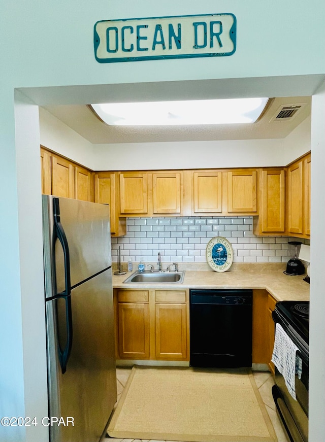 kitchen featuring sink, black appliances, light tile patterned flooring, and backsplash