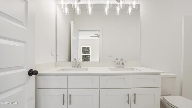 bathroom with double vanity, toilet, and a sink