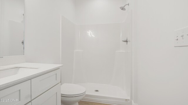 bathroom featuring vanity, a shower stall, and toilet