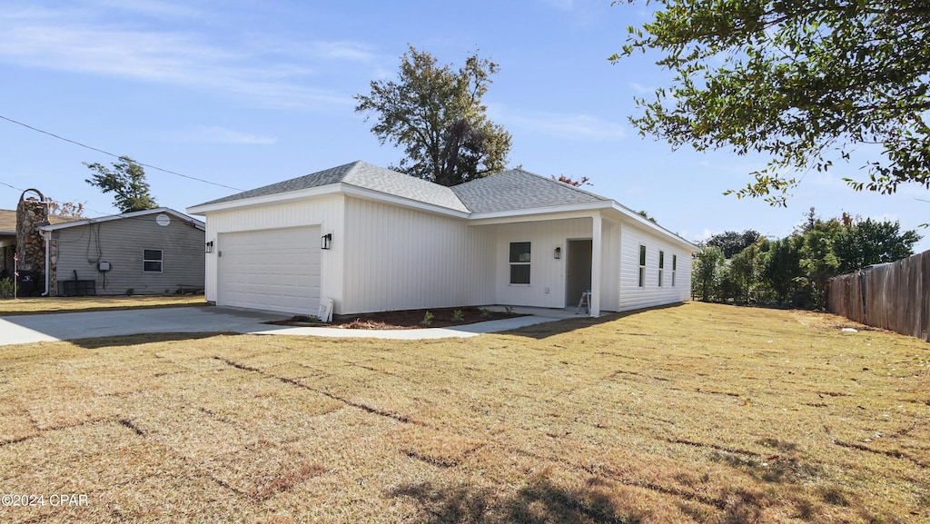 view of front of property featuring a garage, central air condition unit, and a front yard