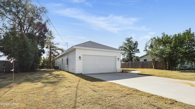 view of home's exterior with fence, a lawn, an outdoor structure, a garage, and driveway