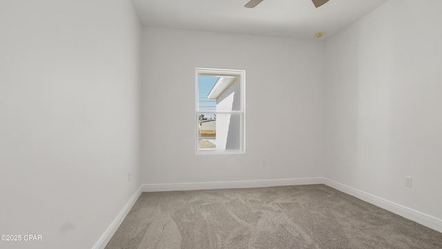 carpeted spare room featuring baseboards and a ceiling fan