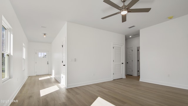 empty room featuring a ceiling fan, baseboards, visible vents, and light wood finished floors