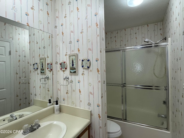 full bathroom with vanity, bath / shower combo with glass door, a textured ceiling, and toilet