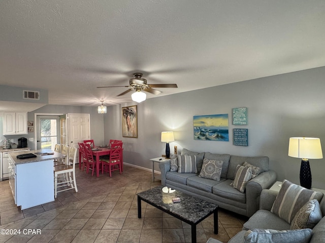 tiled living room with a textured ceiling and ceiling fan