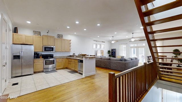 kitchen featuring sink, kitchen peninsula, appliances with stainless steel finishes, light brown cabinets, and light hardwood / wood-style flooring