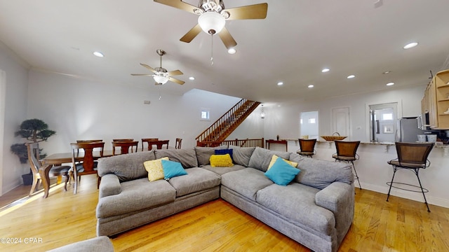 living room featuring light wood-type flooring, ceiling fan, and crown molding