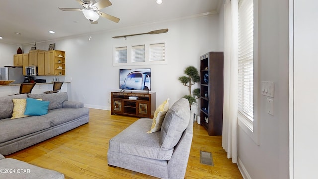 living room featuring light hardwood / wood-style floors, ceiling fan, and ornamental molding