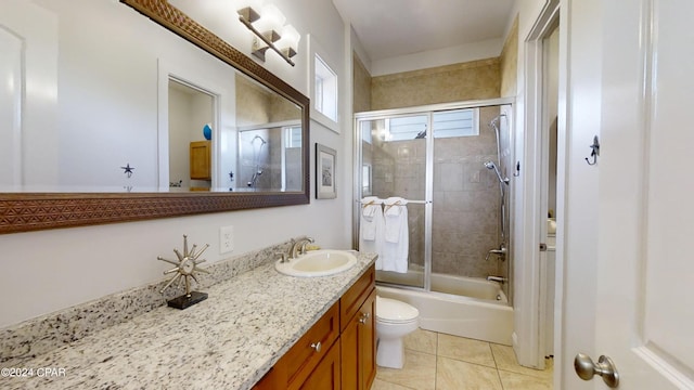 full bathroom with tile patterned flooring, shower / bath combination with glass door, toilet, and vanity