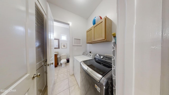 laundry area featuring separate washer and dryer, cabinets, and light tile patterned flooring