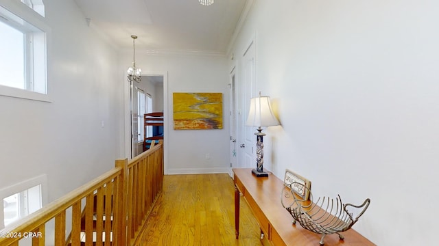 hall with a healthy amount of sunlight, light hardwood / wood-style flooring, and a notable chandelier