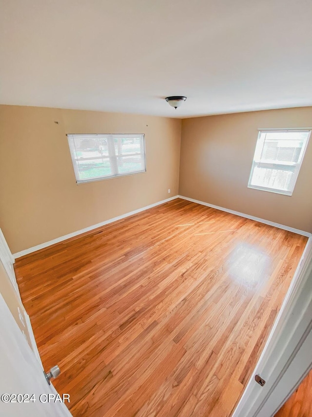 empty room featuring a healthy amount of sunlight, light wood-style floors, and baseboards