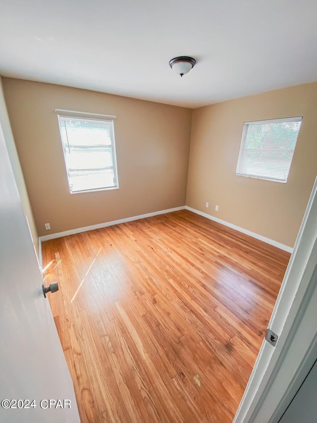 unfurnished room with baseboards, plenty of natural light, and light wood-style floors