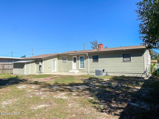 back of property with a chimney, central AC, and fence