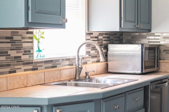 kitchen with dishwasher, tasteful backsplash, sink, and blue cabinets