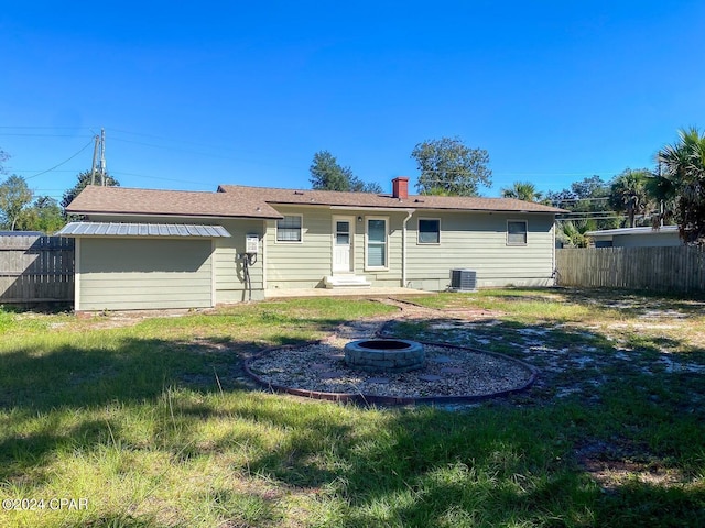 rear view of property with a chimney, a fire pit, and fence