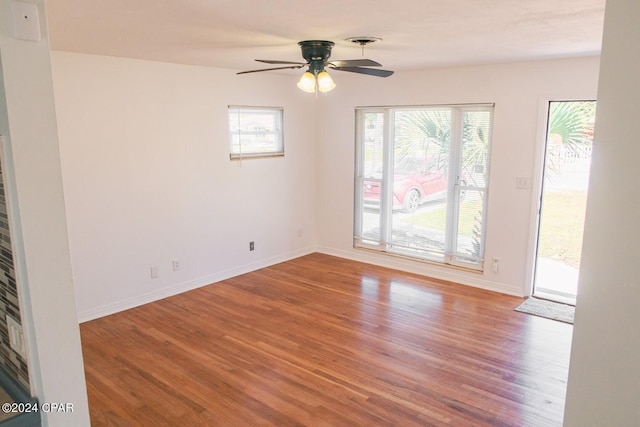 empty room featuring visible vents, wood finished floors, baseboards, and ceiling fan