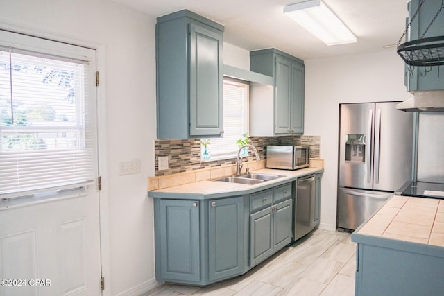 kitchen with a wealth of natural light, backsplash, appliances with stainless steel finishes, and a sink