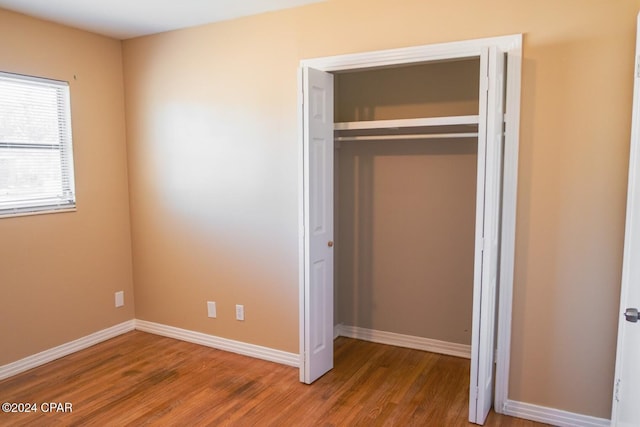 unfurnished bedroom featuring a closet, baseboards, and wood finished floors