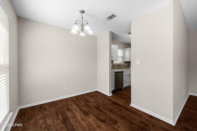 unfurnished dining area with sink, dark wood-type flooring, and a chandelier