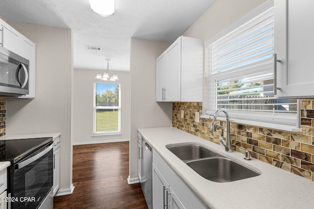 kitchen featuring white cabinetry, hanging light fixtures, sink, appliances with stainless steel finishes, and decorative backsplash